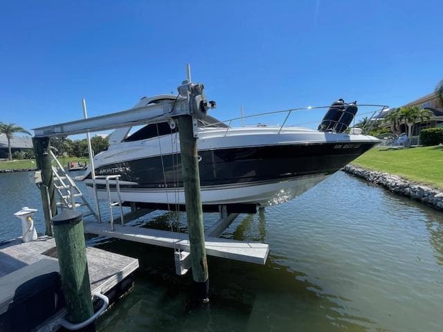 2019 Monterey 295 boat on lift by waterfront dock, sunny day.