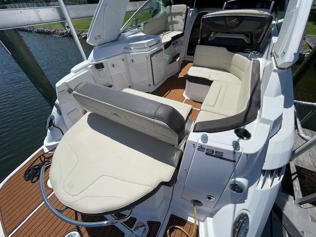 2019 Monterey 295 boat interior with white seating and wood deck, docked by the water.