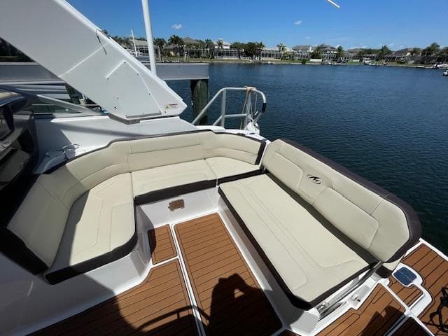 2019 Monterey 295 boat with beige seating, docked by a scenic waterfront.