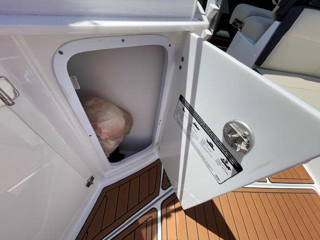 Open storage compartment on 2019 Monterey 295 boat with wooden flooring.