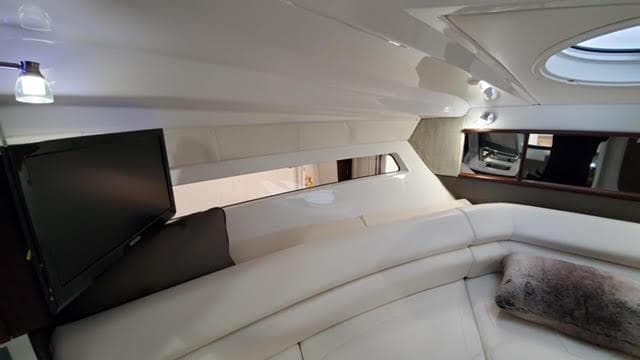 Luxurious interior of a 2019 Monterey 295 boat with plush seating and a mounted TV.