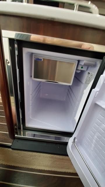 Open mini fridge inside 2019 Monterey 295 boat, showing empty interior and shelves.