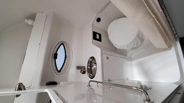 2019 Monterey 295 boat interior with porthole, sink, and compact bathroom amenities.