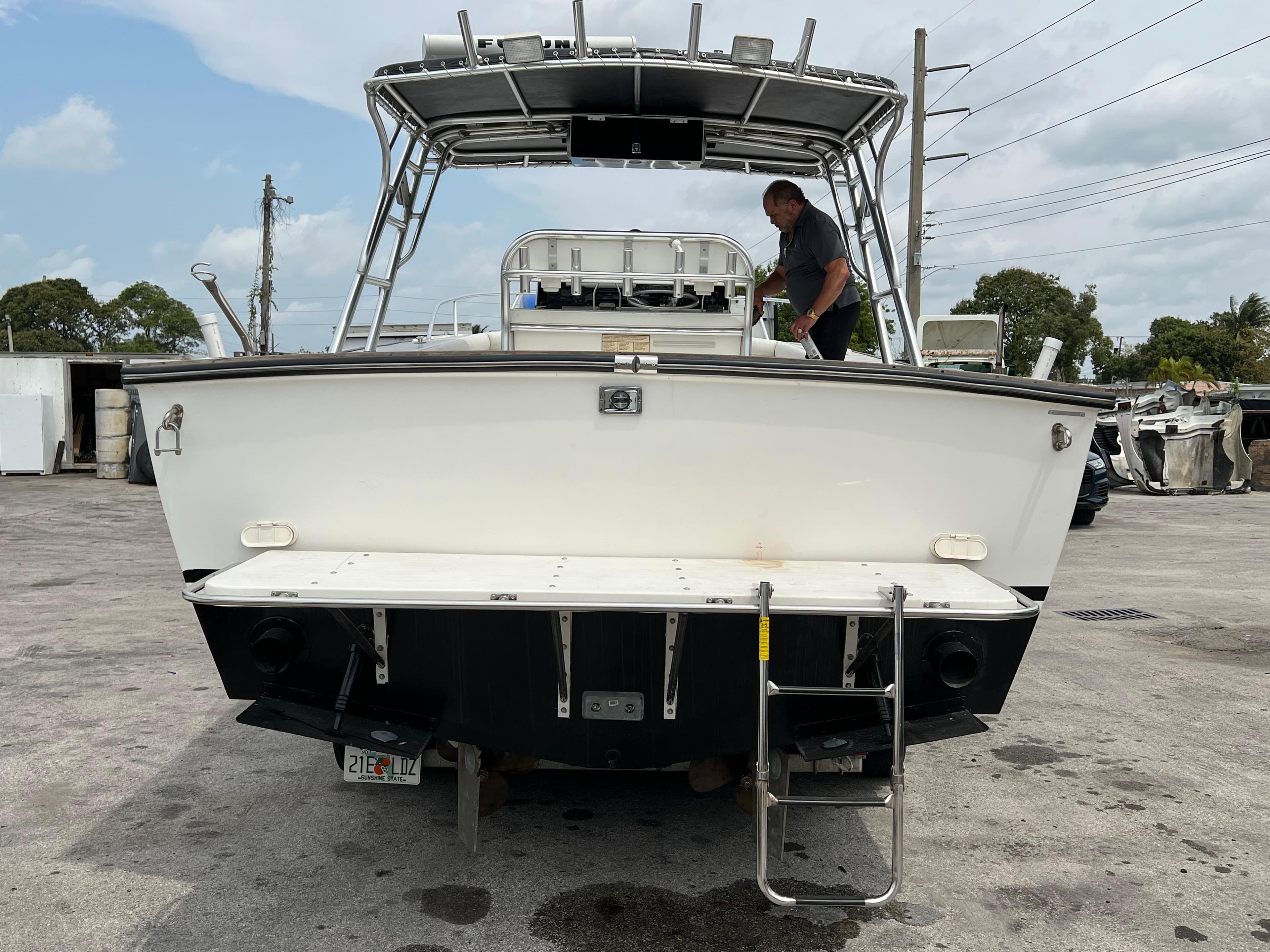 2000 Stuart Angler 32 Center Console boat with ladder, docked on concrete surface.