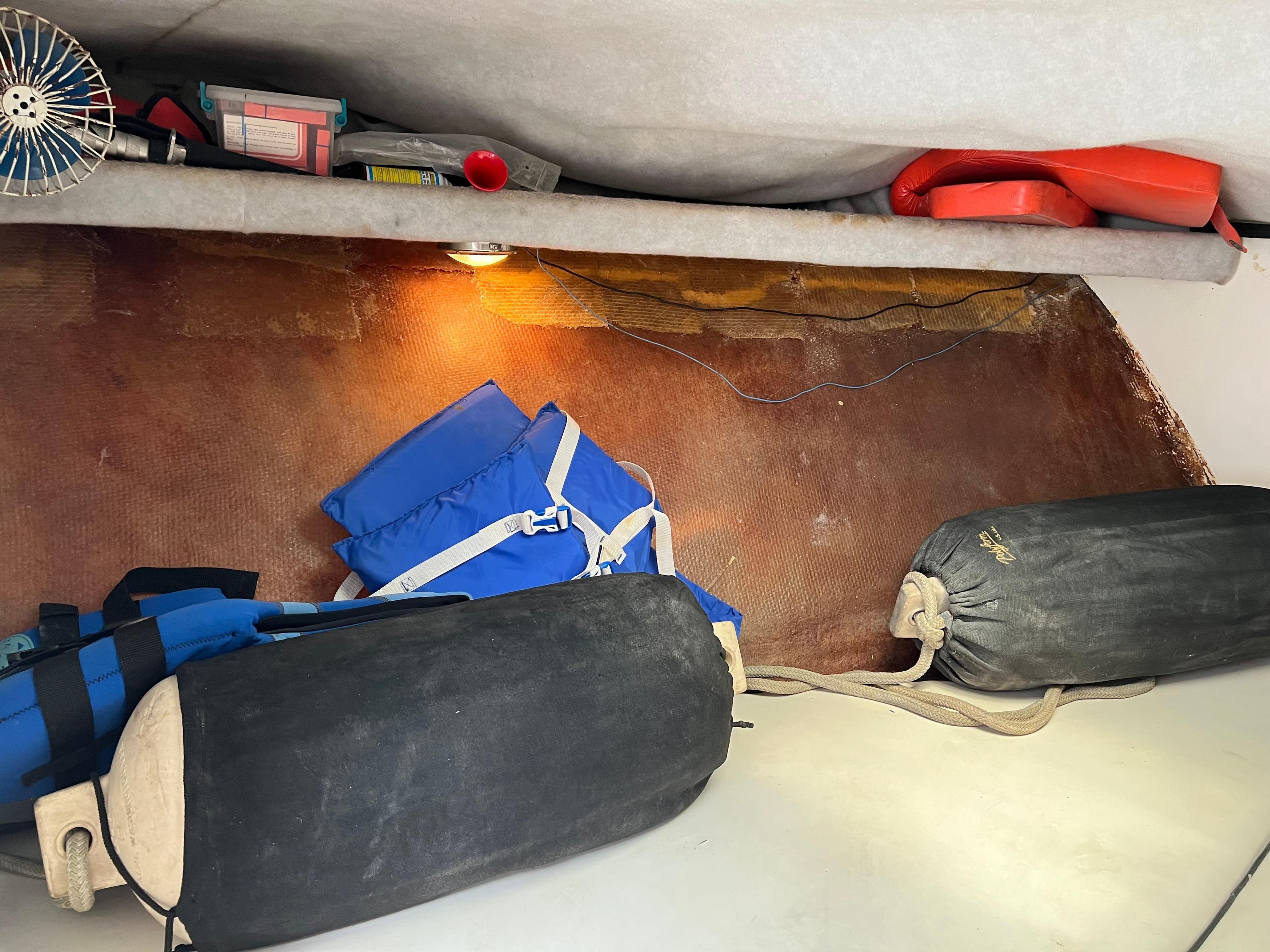 Interior of 2000 Stuart Angler boat with life jackets, fenders, and storage items.