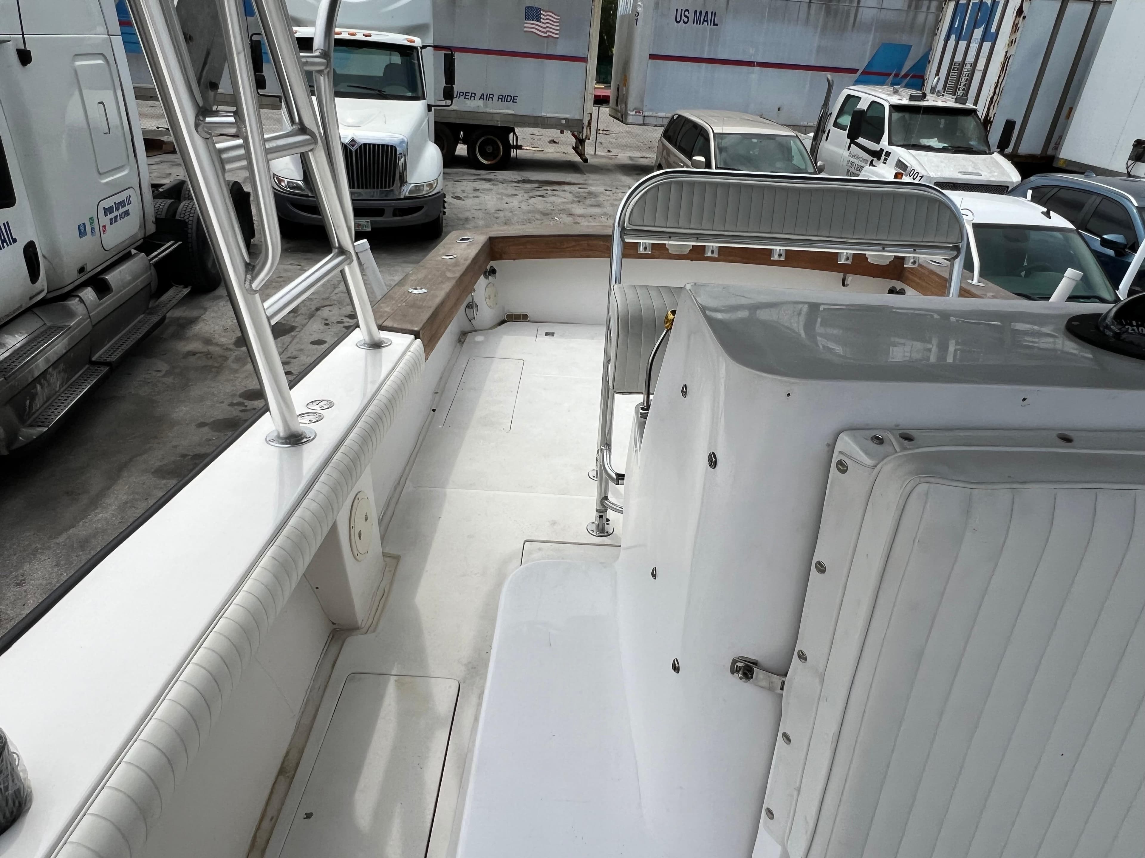 2000 Stuart Angler 32 Center Console boat interior with seating and railing, parked near trucks.