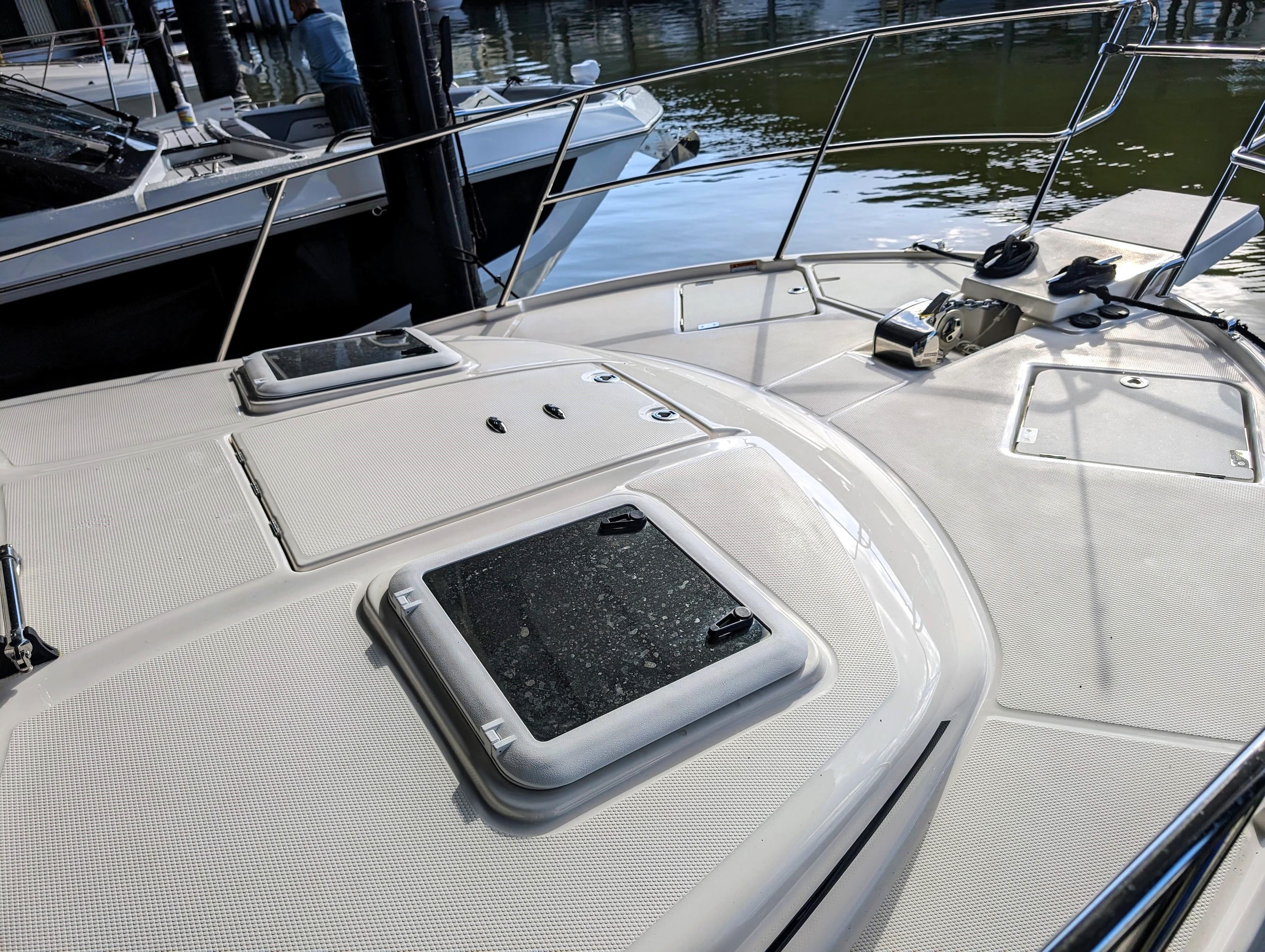 2022 Cutwater C-32 Coupe LE boat deck with hatches and railing at marina.