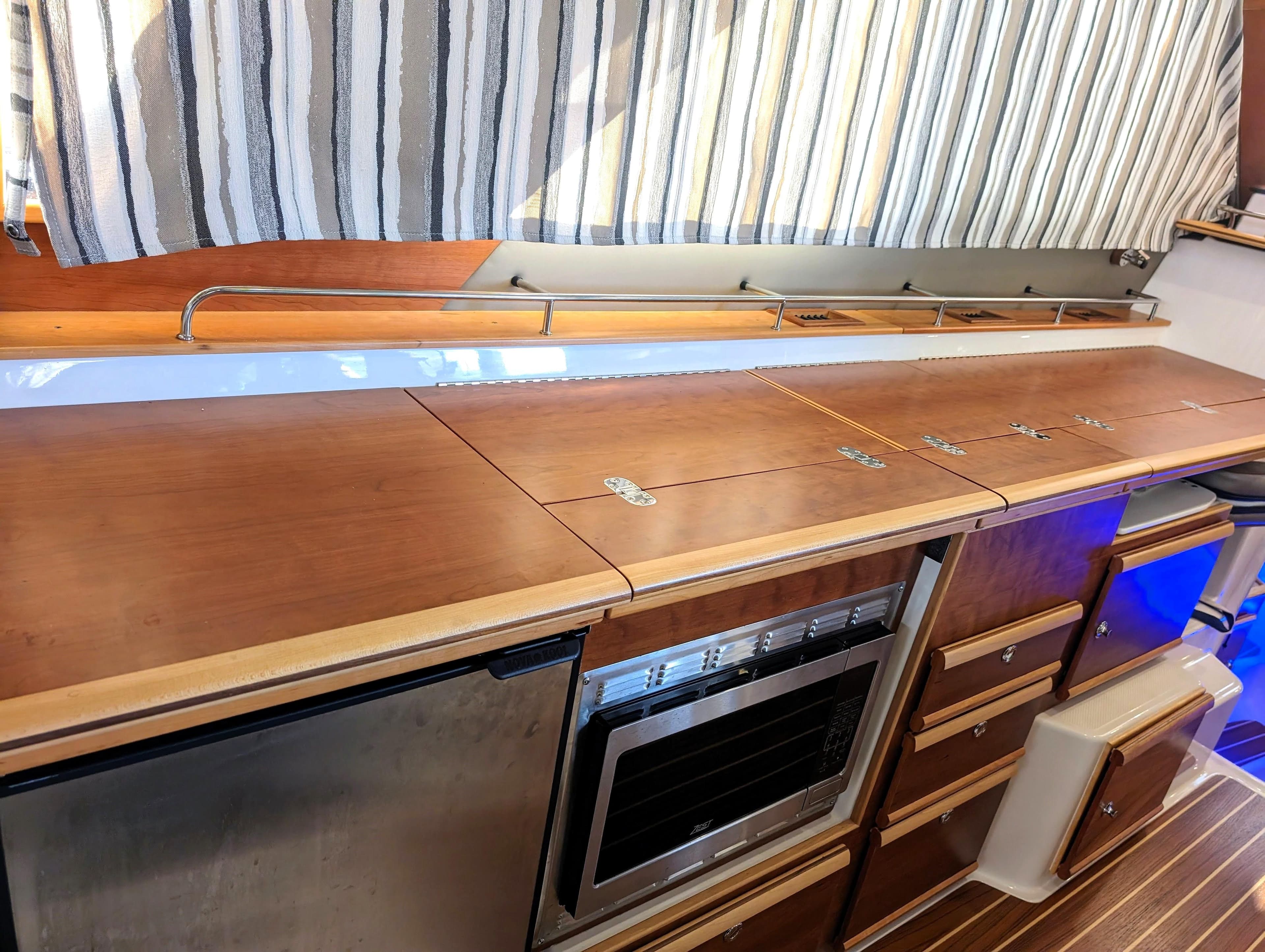 2022 Cutwater C-32 Coupe LE kitchen area with wooden cabinets and stainless steel appliances.