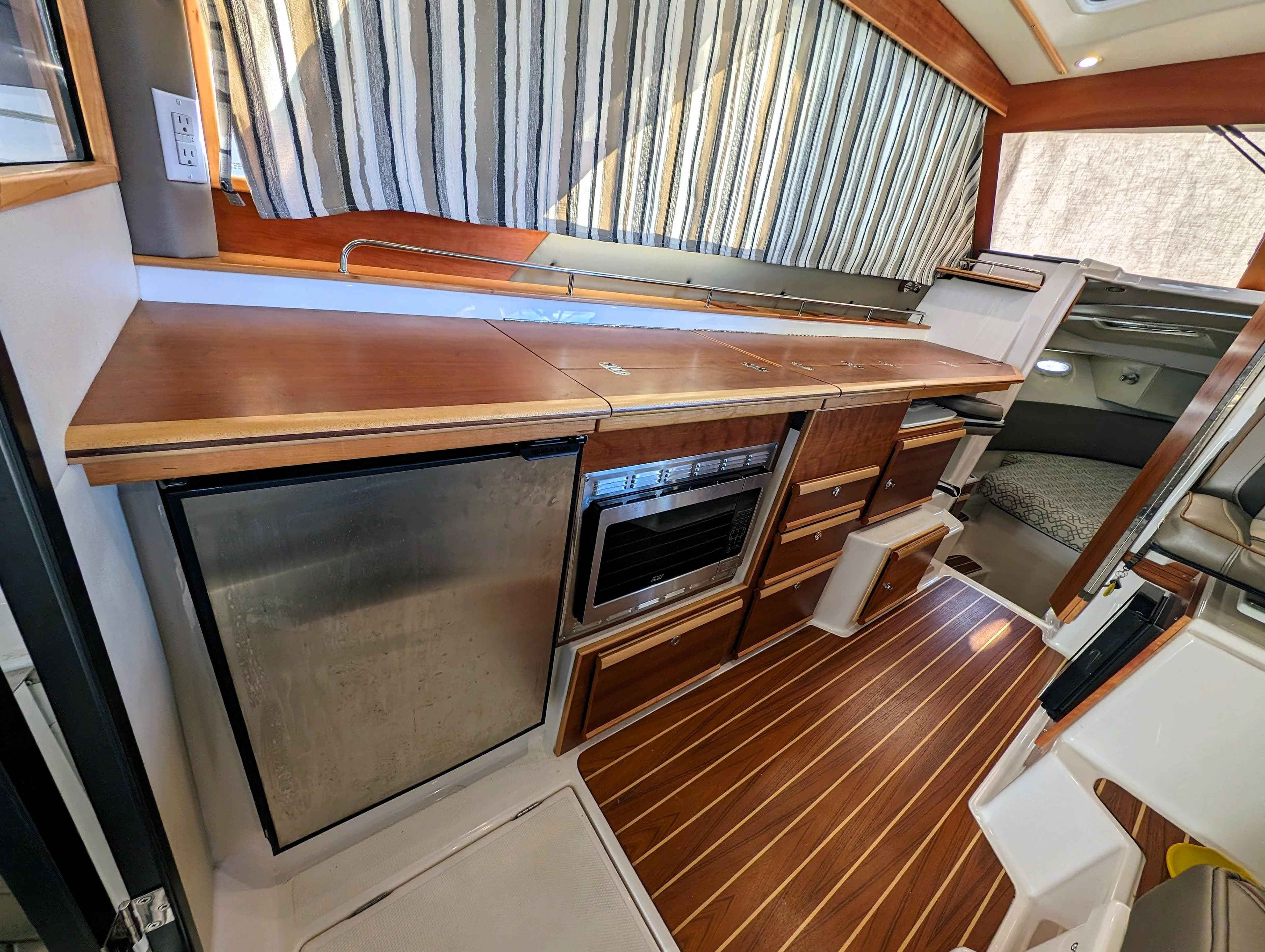 2022 Cutwater C-32 Coupe LE interior kitchen with wood cabinetry and stainless steel appliances.