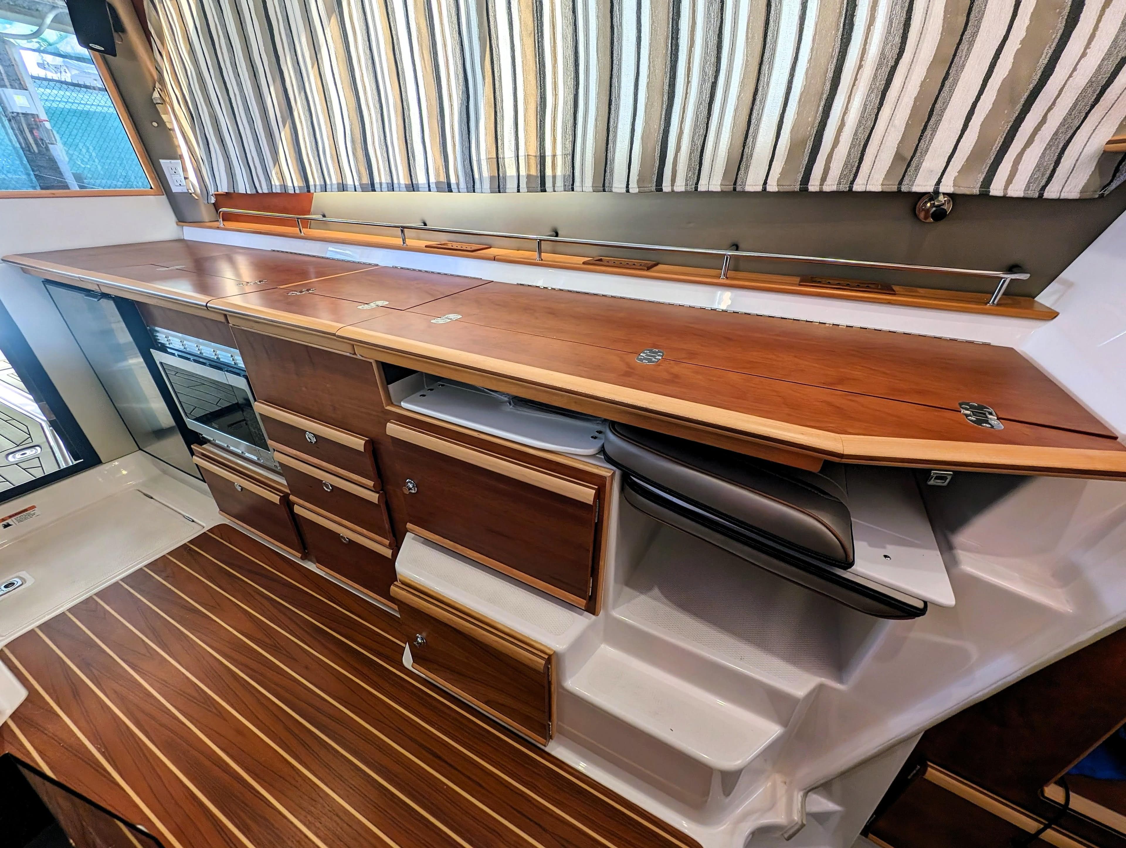 Interior of 2022 Cutwater C-32 Coupe LE with wooden cabinetry and striped curtains.