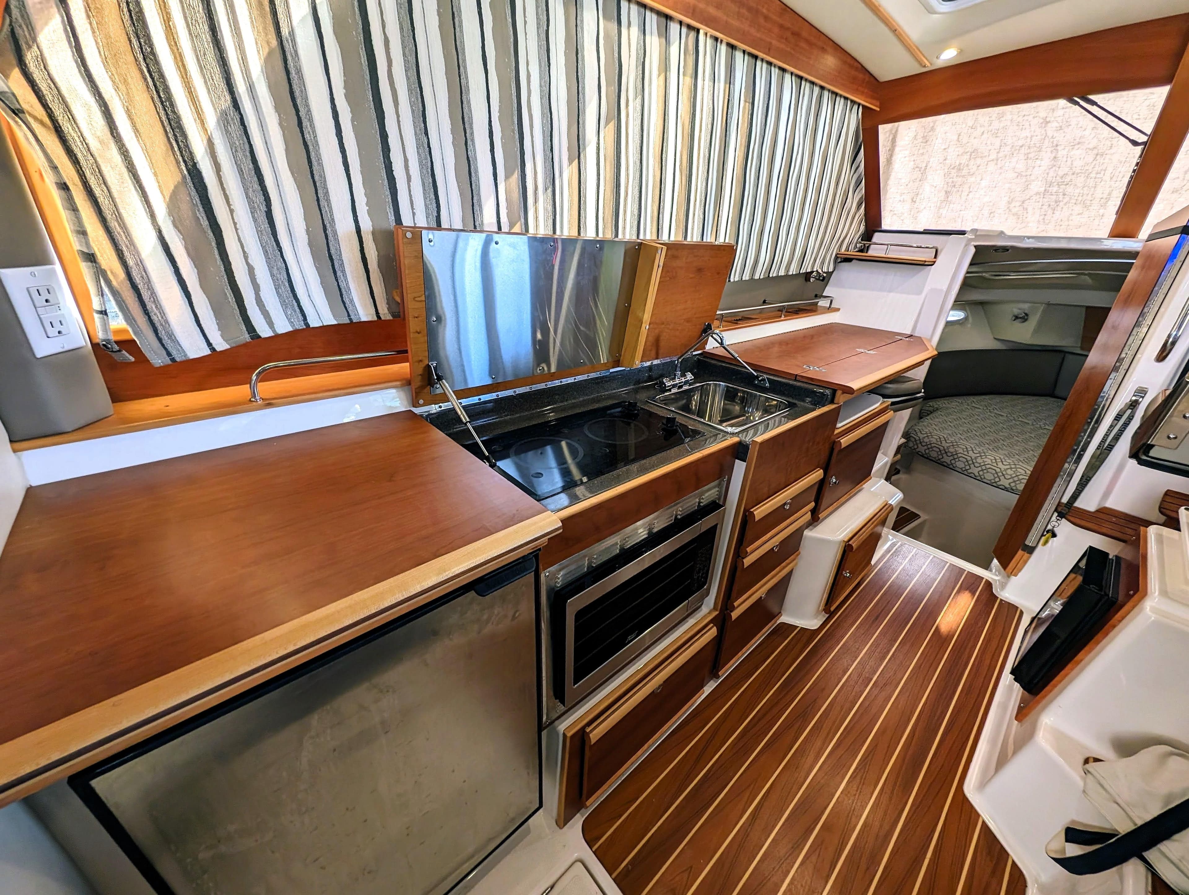 Interior of 2022 Cutwater C-32 Coupe LE, featuring a modern kitchen and cozy sleeping area.