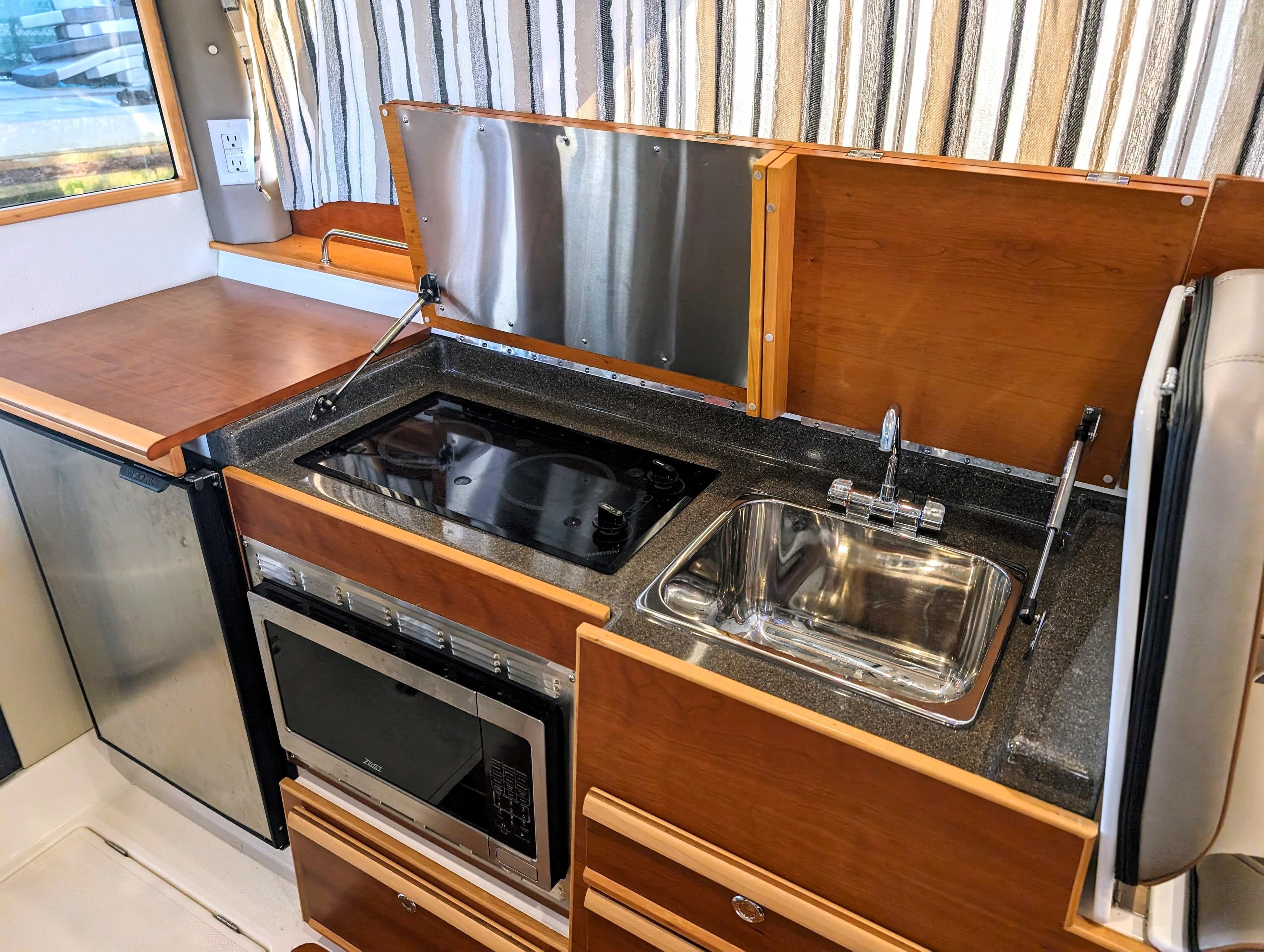 2022 Cutwater C-32 Coupe LE galley with stove, sink, microwave, and refrigerator.