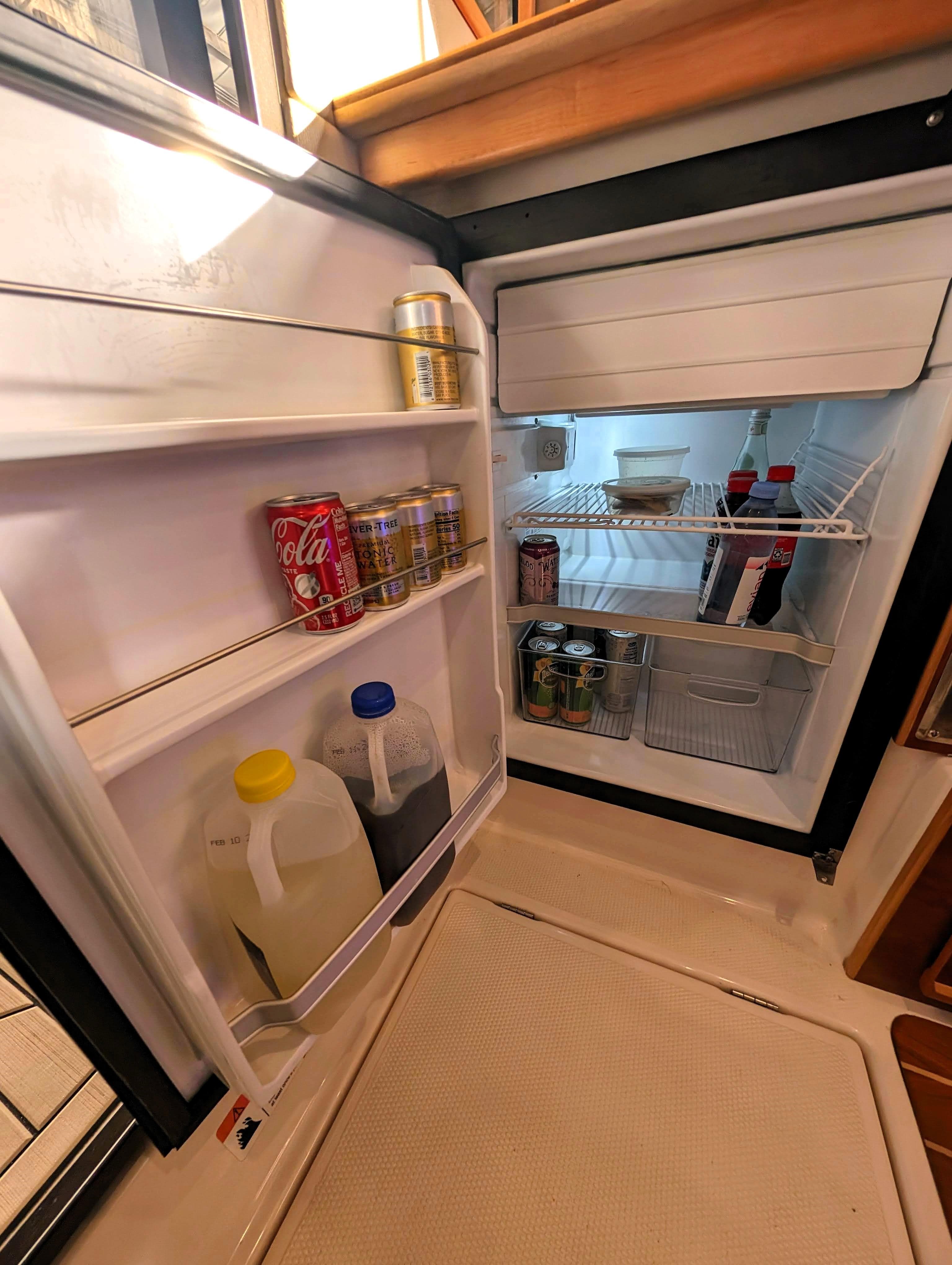 Open refrigerator in 2022 Cutwater C-32 Coupe LE boat, stocked with beverages and food.